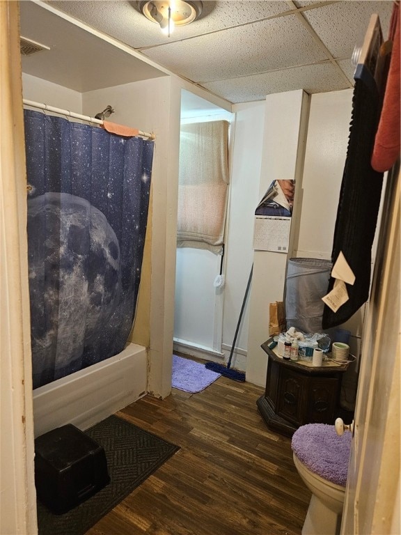 bathroom with shower / tub combo, wood-type flooring, a drop ceiling, and toilet