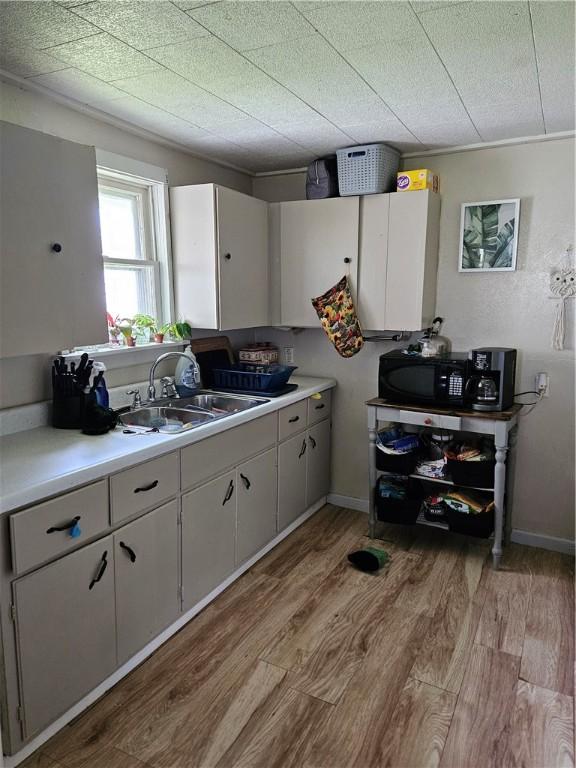 kitchen with light hardwood / wood-style flooring, white cabinets, and sink