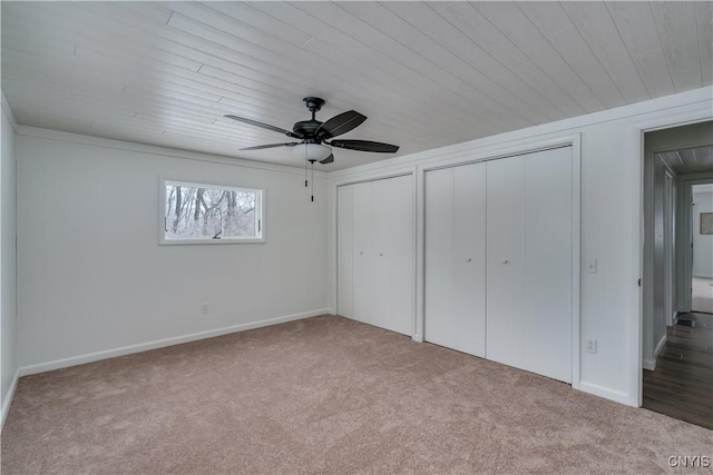 unfurnished bedroom with light carpet, a ceiling fan, and multiple closets