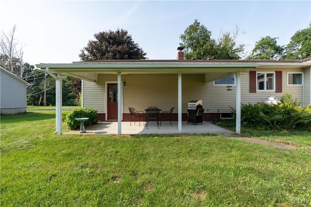 rear view of property with a patio area, a chimney, and a yard