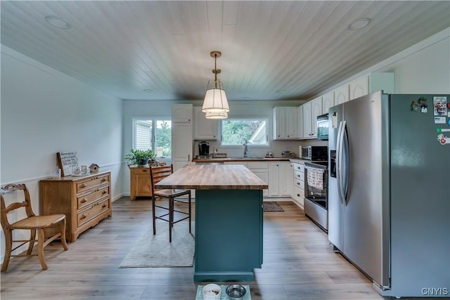 kitchen with decorative light fixtures, stainless steel appliances, butcher block counters, white cabinetry, and a kitchen island