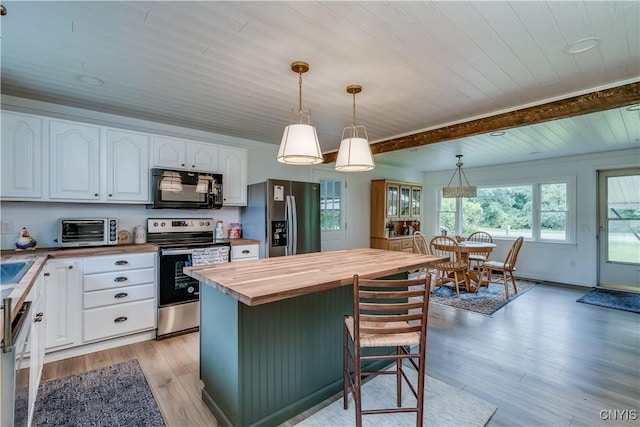 kitchen with stainless steel appliances, white cabinets, wooden counters, and hanging light fixtures