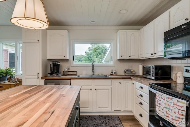 kitchen with butcher block counters, appliances with stainless steel finishes, white cabinets, and a sink