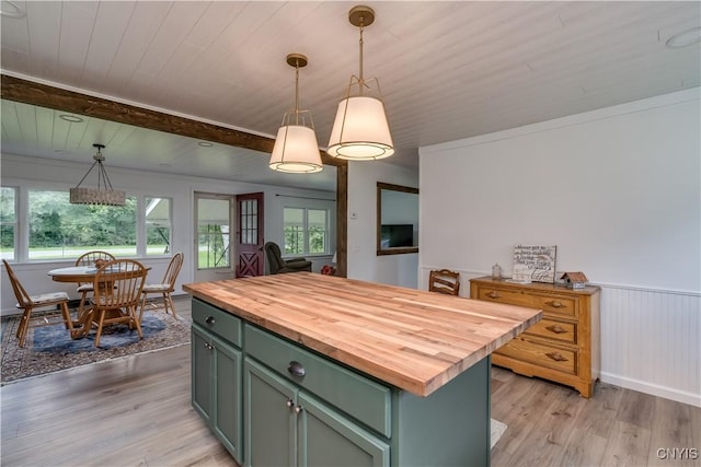 kitchen with hanging light fixtures, butcher block counters, green cabinets, and a center island