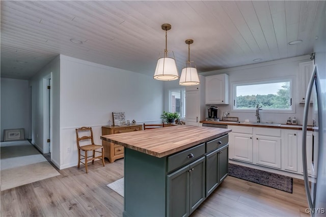 kitchen featuring wood counters, white cabinetry, hanging light fixtures, a center island, and light wood finished floors