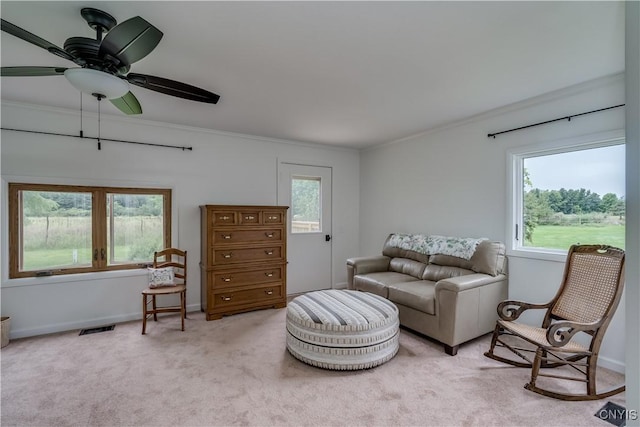 living area with light colored carpet, visible vents, ornamental molding, ceiling fan, and baseboards