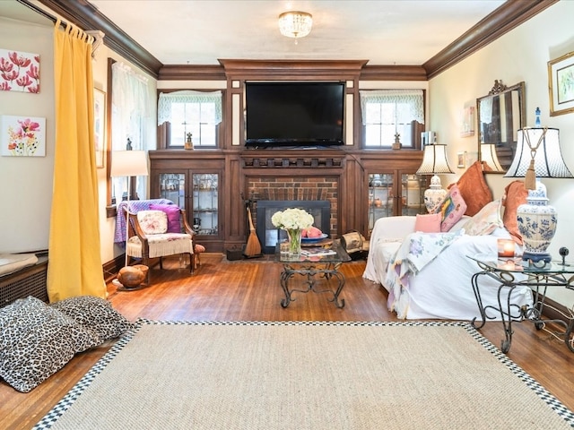 living room featuring a brick fireplace, crown molding, hardwood / wood-style flooring, and a wealth of natural light