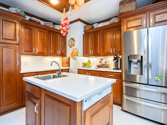 kitchen featuring decorative backsplash, crown molding, stainless steel fridge, an island with sink, and sink