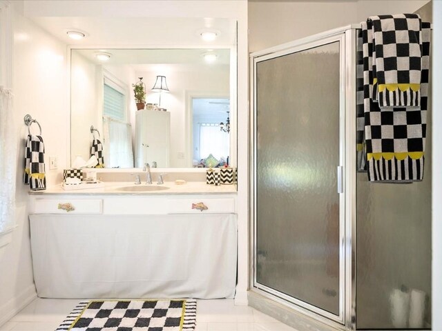 bathroom with a shower with shower door, vanity, and tile patterned flooring