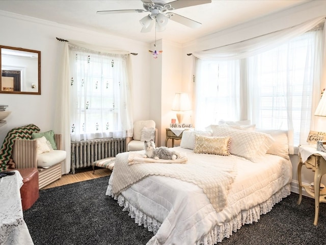 bedroom with radiator heating unit, ornamental molding, and multiple windows