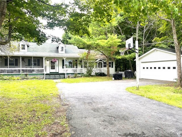 view of front facade featuring a front yard, covered porch, a garage, and an outbuilding