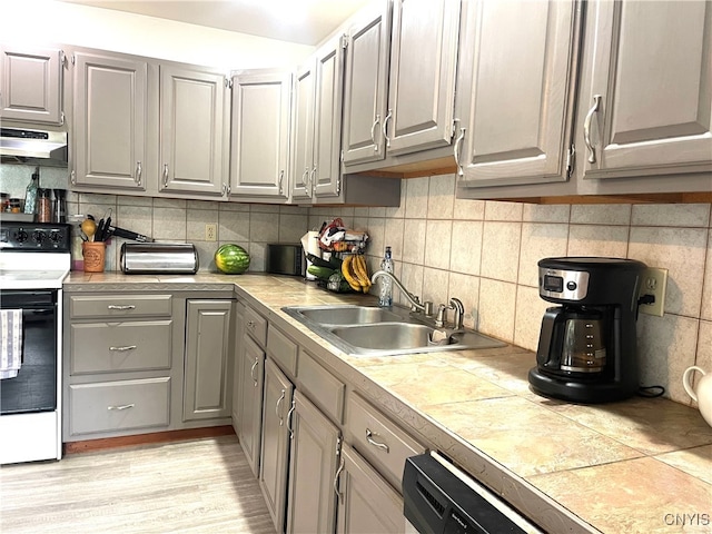 kitchen featuring white electric range oven, gray cabinets, light wood-type flooring, tasteful backsplash, and sink