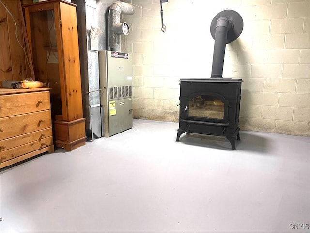 interior space with heating unit, concrete block wall, and a wood stove