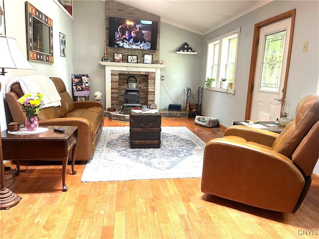 living room featuring crown molding, vaulted ceiling, light hardwood / wood-style floors, and a wood stove