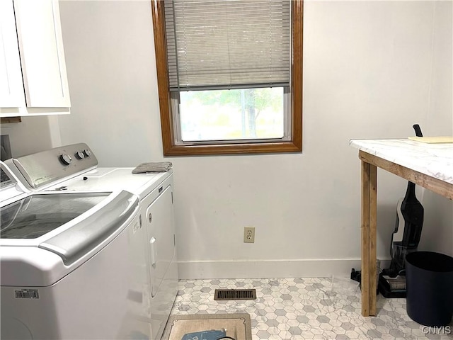 laundry area featuring washer and dryer, visible vents, cabinet space, and baseboards