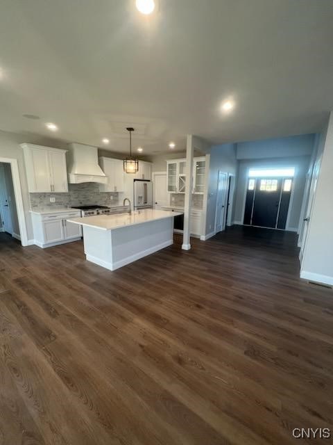 kitchen featuring premium range hood, a sink, white cabinetry, white fridge with ice dispenser, and light countertops