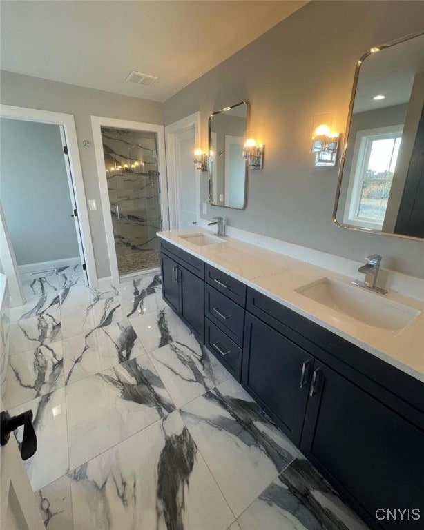 bathroom with double vanity, marble finish floor, tiled shower, and a sink