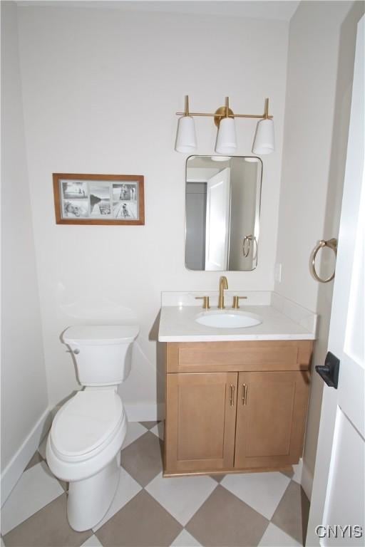 bathroom with tile patterned floors, baseboards, toilet, and vanity