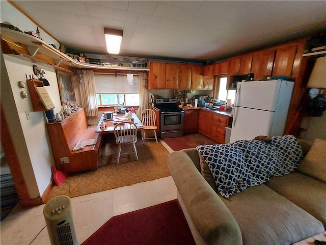 kitchen with electric stove, light tile patterned floors, and white fridge