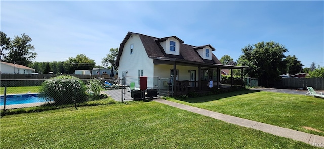 back of property with a fenced in pool, covered porch, and a yard