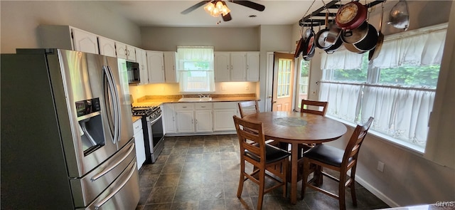 kitchen featuring white cabinets, stainless steel appliances, dark tile patterned floors, and ceiling fan