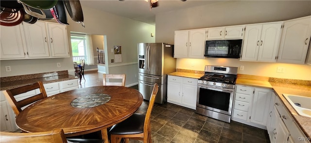 kitchen with appliances with stainless steel finishes, sink, dark tile patterned flooring, and white cabinetry