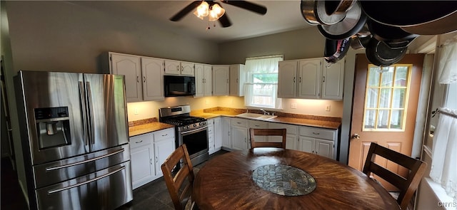 kitchen with sink, stainless steel appliances, dark tile patterned floors, and white cabinetry