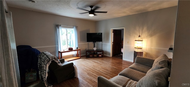 living room with ceiling fan, hardwood / wood-style flooring, and a textured ceiling