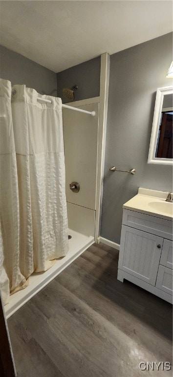 bathroom with walk in shower, vanity, and hardwood / wood-style floors