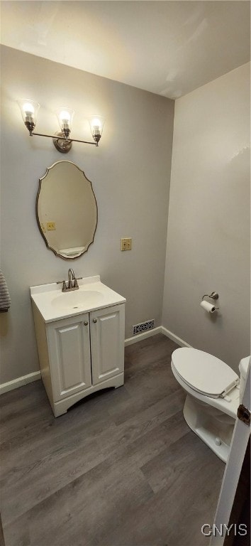 bathroom with hardwood / wood-style flooring, vanity, and toilet