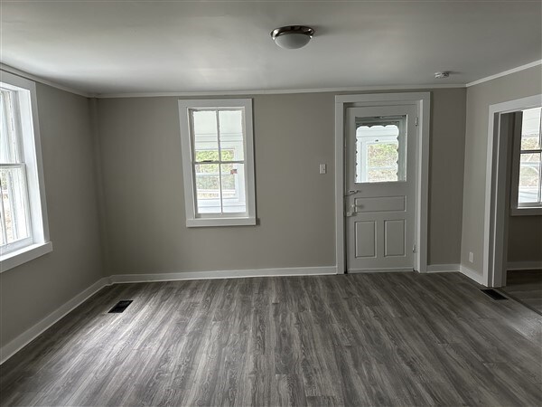 entrance foyer with dark hardwood / wood-style flooring, crown molding, and plenty of natural light