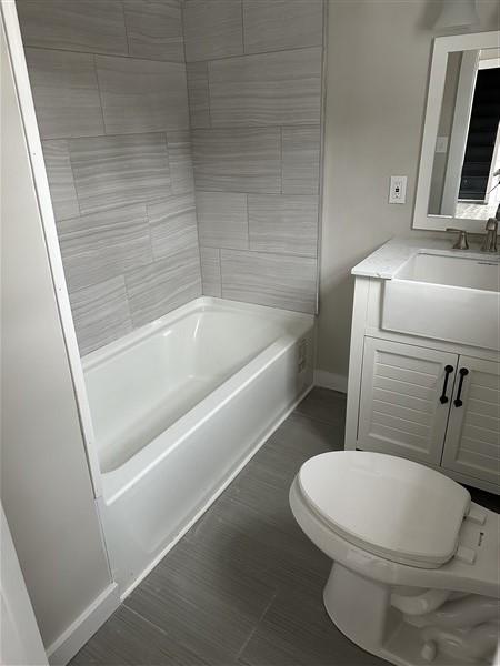 full bathroom with tiled shower / bath, vanity, and toilet