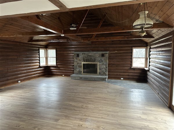 unfurnished living room with hardwood / wood-style flooring, a healthy amount of sunlight, lofted ceiling with beams, and wooden ceiling