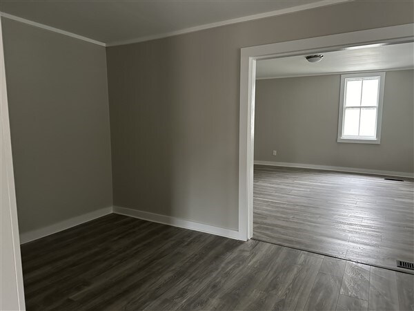 spare room featuring crown molding and dark wood-type flooring