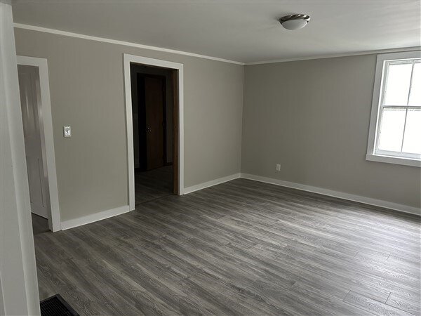 unfurnished room with ornamental molding and dark wood-type flooring