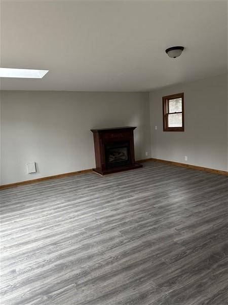 unfurnished living room with hardwood / wood-style flooring and a skylight