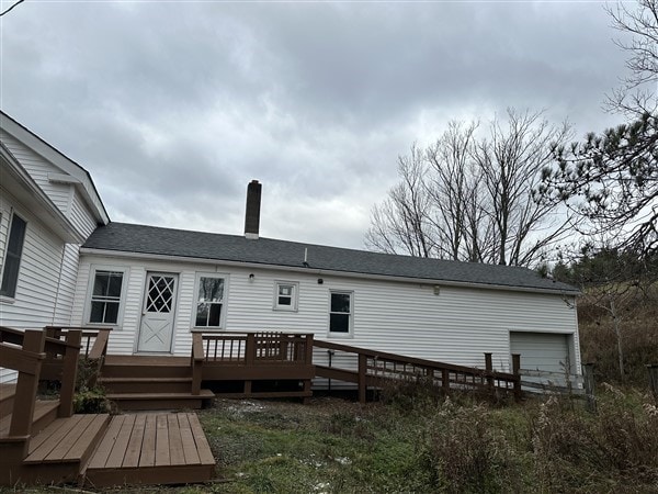 rear view of property featuring a garage and a deck