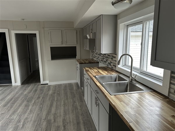 kitchen featuring wood counters, sink, dark hardwood / wood-style floors, gray cabinets, and backsplash