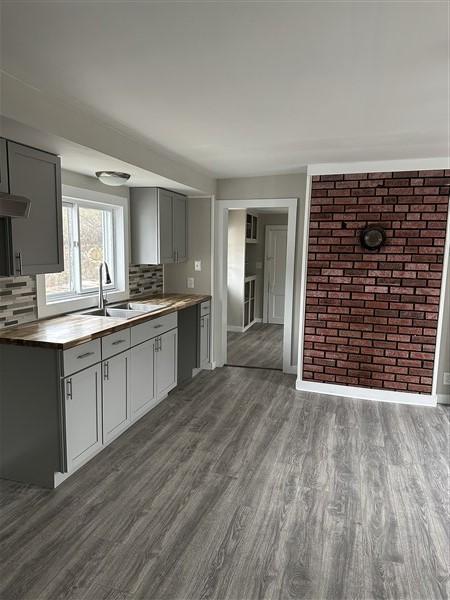 kitchen featuring gray cabinets, wood-type flooring, sink, and tasteful backsplash