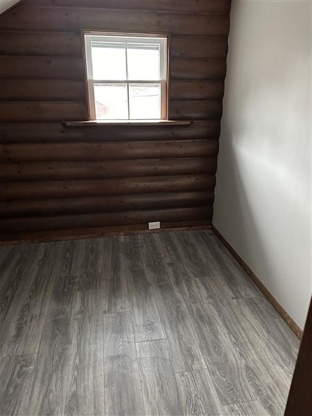 interior space featuring dark wood-type flooring and rustic walls