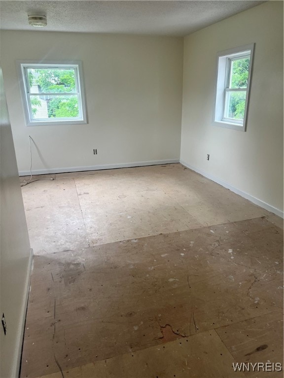 unfurnished room featuring a textured ceiling and a wealth of natural light