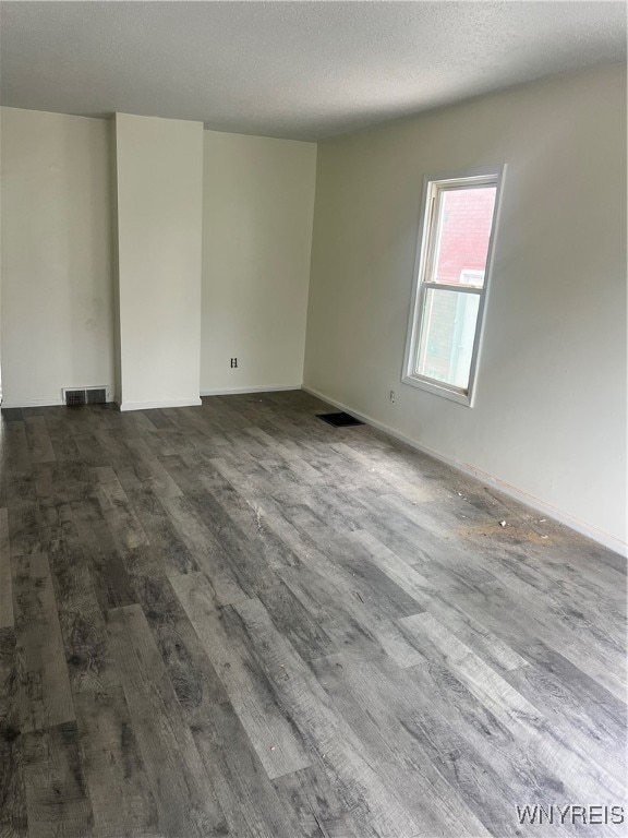 empty room with wood-type flooring and a textured ceiling