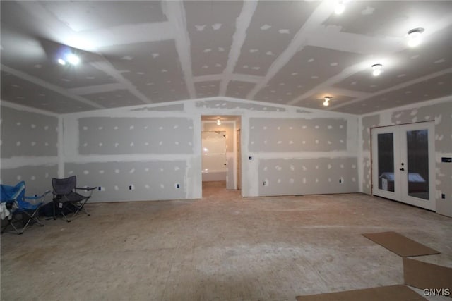 unfurnished living room featuring vaulted ceiling and french doors