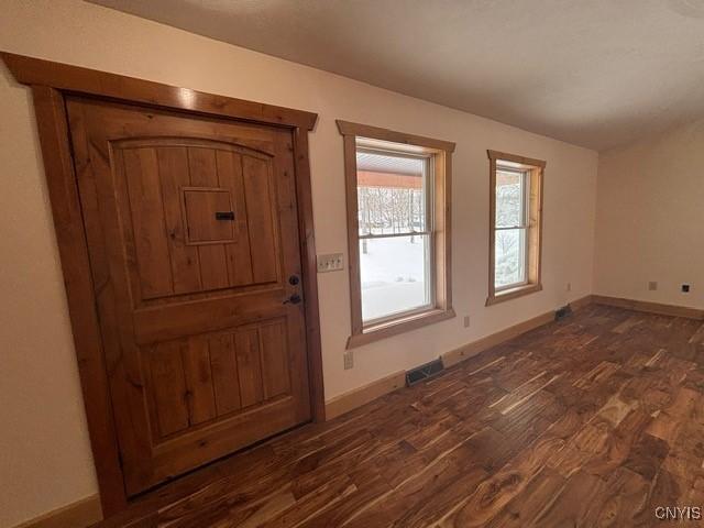 foyer entrance with visible vents, baseboards, and dark wood-type flooring