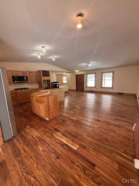 kitchen with dark wood finished floors, stainless steel appliances, lofted ceiling, open floor plan, and baseboards