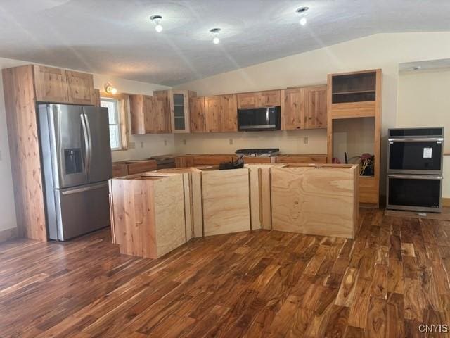 kitchen featuring lofted ceiling, appliances with stainless steel finishes, dark wood-type flooring, and a kitchen island