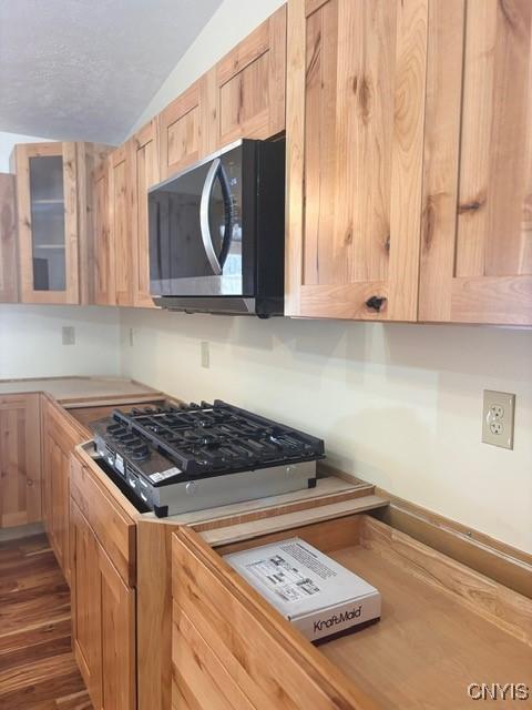 kitchen featuring light brown cabinets, glass insert cabinets, light countertops, and dark wood-type flooring