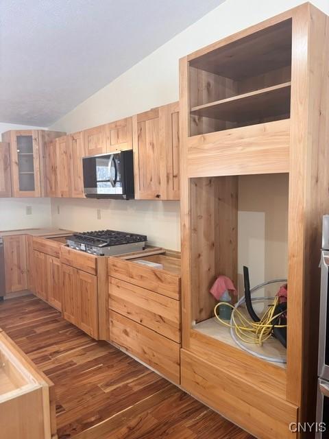 kitchen featuring lofted ceiling, dark wood-style flooring, light brown cabinets, and glass insert cabinets