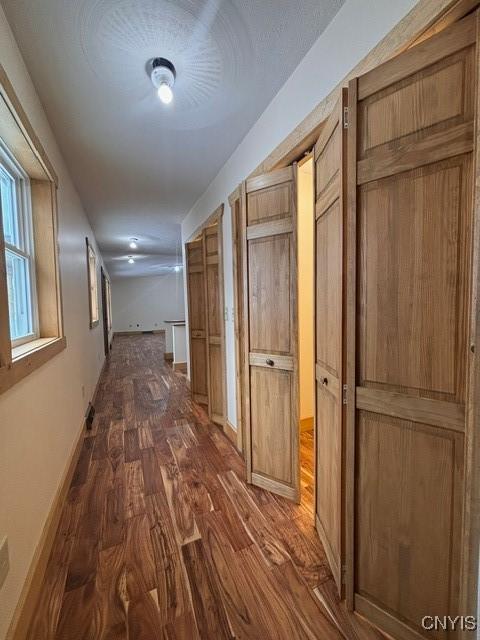 hallway featuring baseboards and dark wood-style flooring