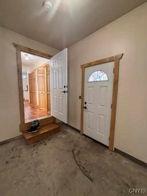 entrance foyer featuring baseboards and unfinished concrete flooring